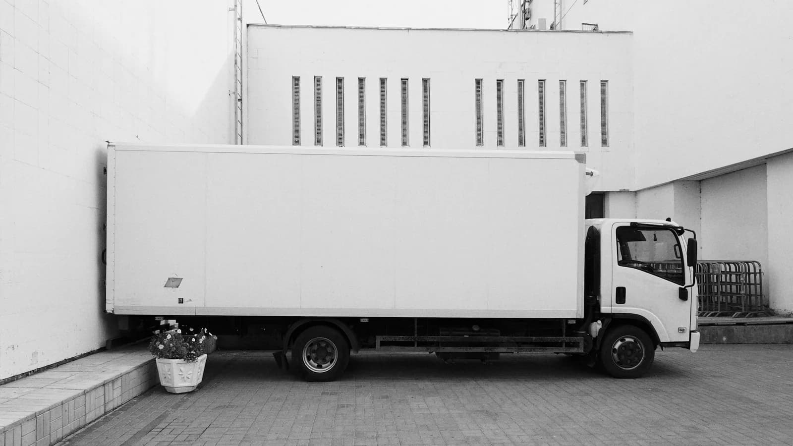 White box truck parked beside a warehouse